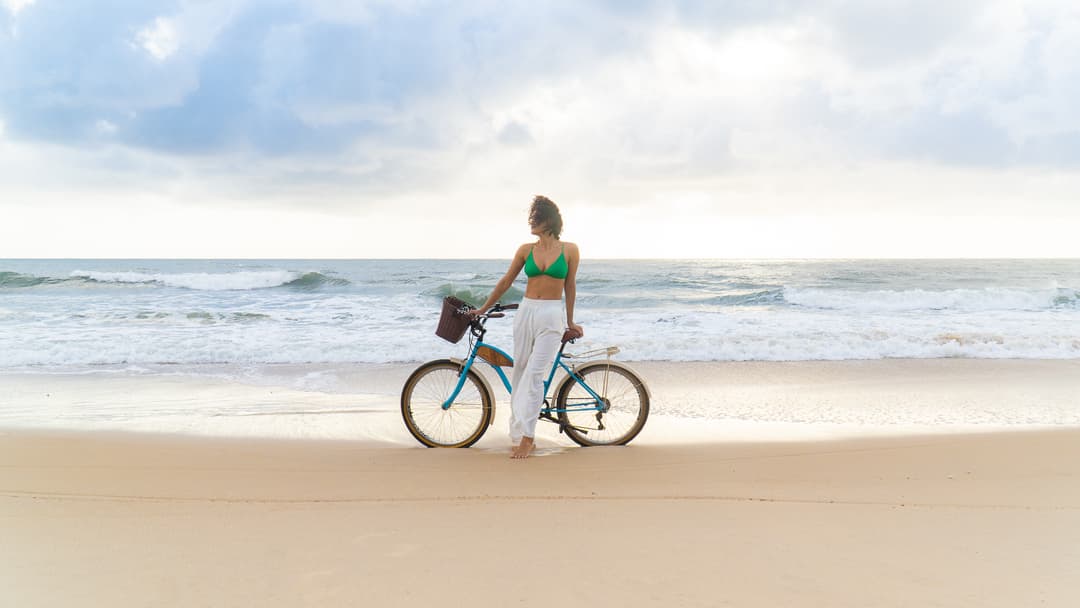 Mulher com bicicleta na praia de Sibaúma ao amanhecer