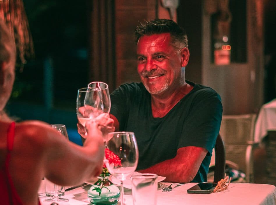 Homem sorrindo brindando com taça de vinho em jantar noturno no restaurante Kibo