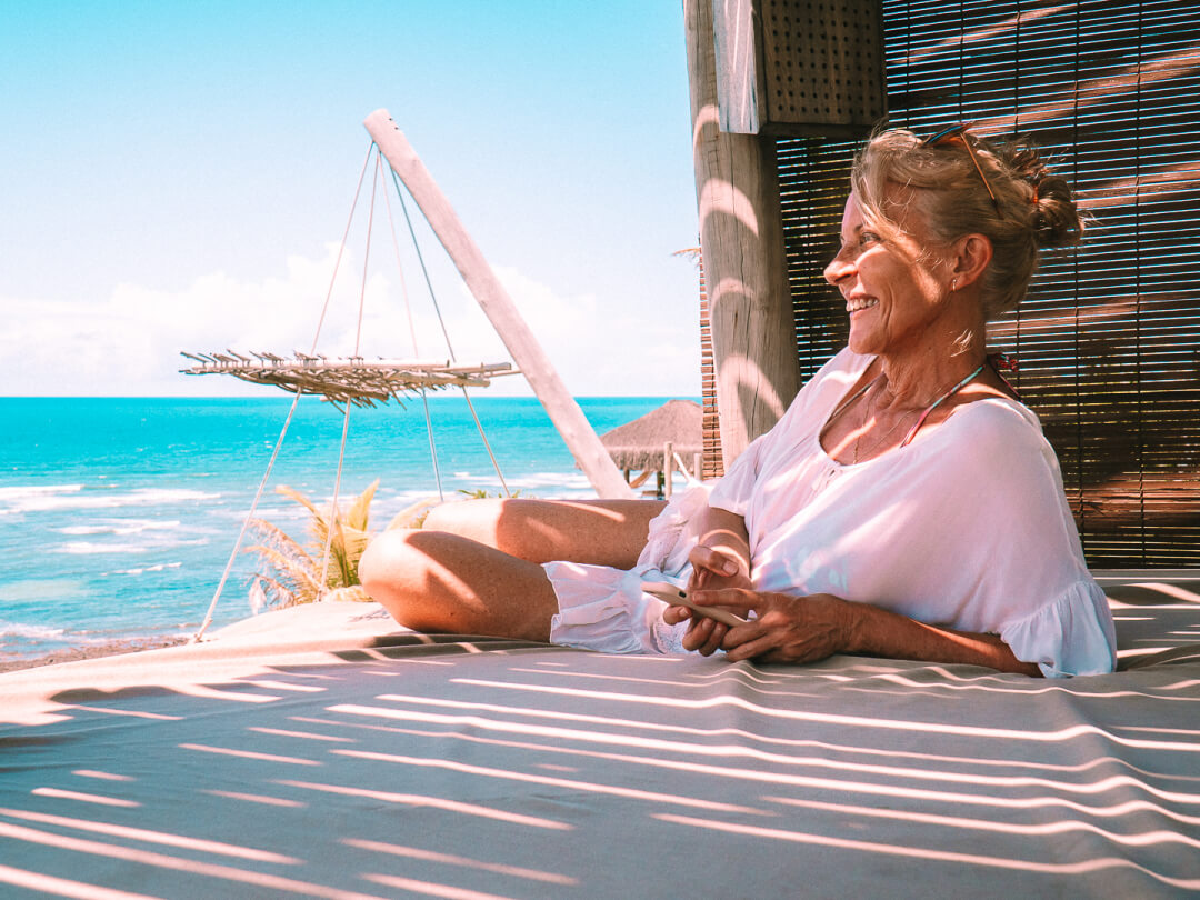 Senhora sorrindo e vendo o horizonte no bangalô do Kilombo Villas.